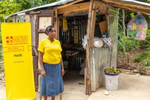 Chrismène Laureus Jusné devant sa boutique, à côté de la bannière d'ASB, à Camp-Perrin.